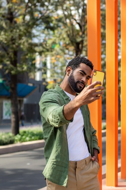 Foto joven hispano tomándose un selfie en la calle