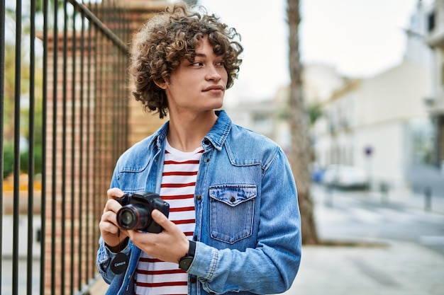 Joven hispano usando cámara fotográfica en la ciudad