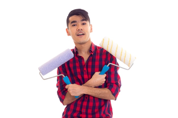 Joven hombre agradable con cabello negro en camisa a cuadros roja con rollo sobre fondo blanco en el estudio