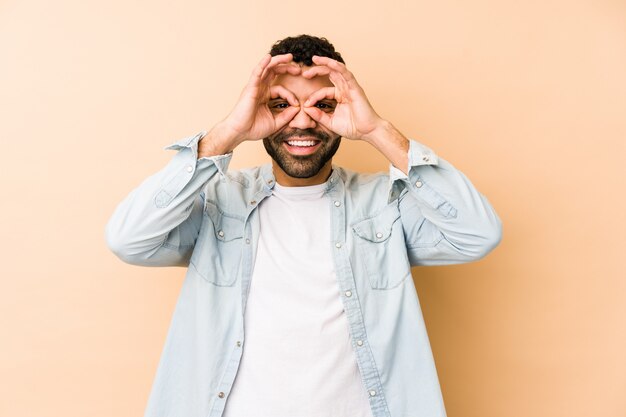 Joven hombre árabe de raza mixta mostrando signo bien sobre los ojos