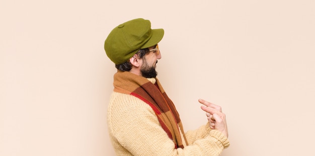 Joven hombre barbudo fresco que parece orgulloso, positivo y casual apuntando al pecho con ambas manos