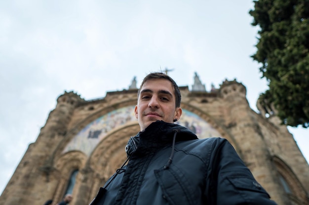 Joven hombre de cabello castaño frente a la iglesia mirando a la cámara Winter