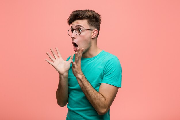 Foto joven hombre caucásico fresco grita fuerte, mantiene los ojos abiertos y las manos tensas.