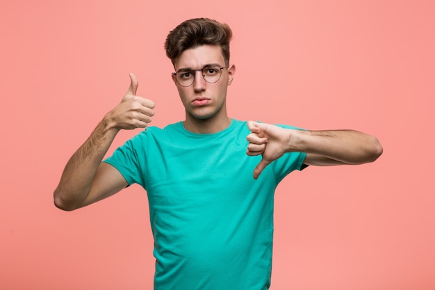 Joven hombre caucásico fresco mostrando pulgares arriba y pulgares abajo