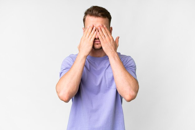 Foto joven hombre caucásico guapo sobre un fondo blanco aislado cubriendo los ojos con las manos