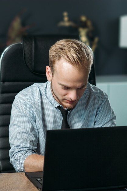 Joven hombre caucásico que trabaja en la oficina con un ordenador portátil el concepto de un empleado de Europa