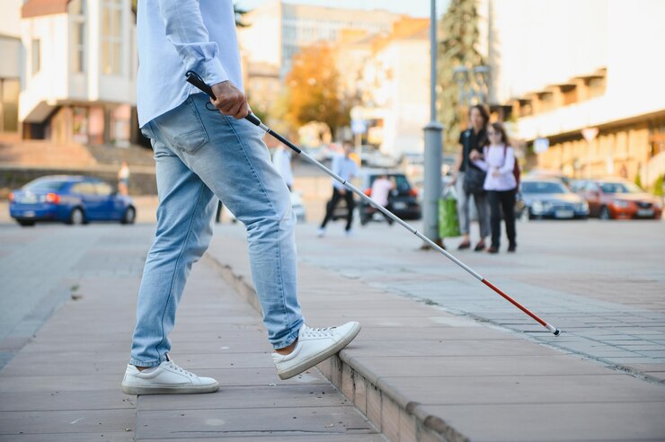 Foto joven hombre ciego y guapo caminando con un palo por la ciudad.