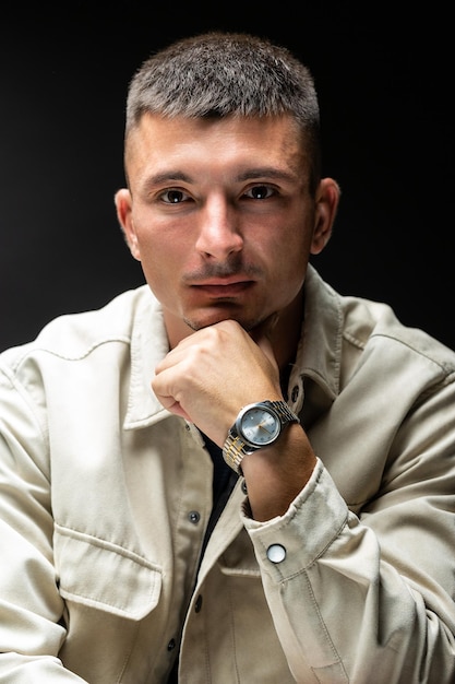 Joven hombre elegante y exitoso Retrato clásico de un hombre de negocios vestido con una chaqueta con un reloj en la mano