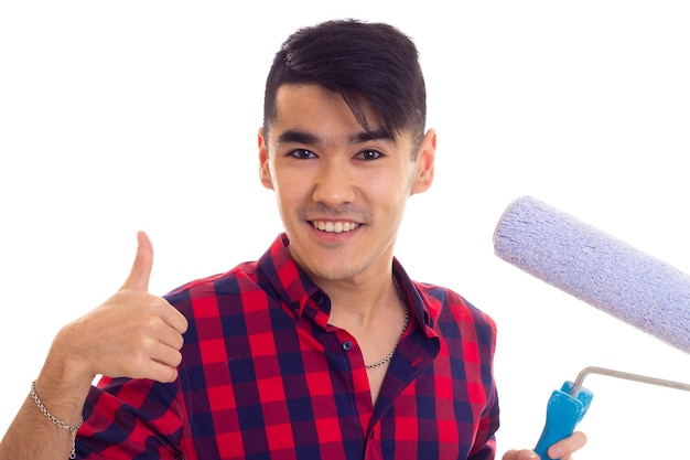 Joven hombre feliz con cabello oscuro en camisa roja a cuadros con rollo azul sobre fondo blanco en el estudio