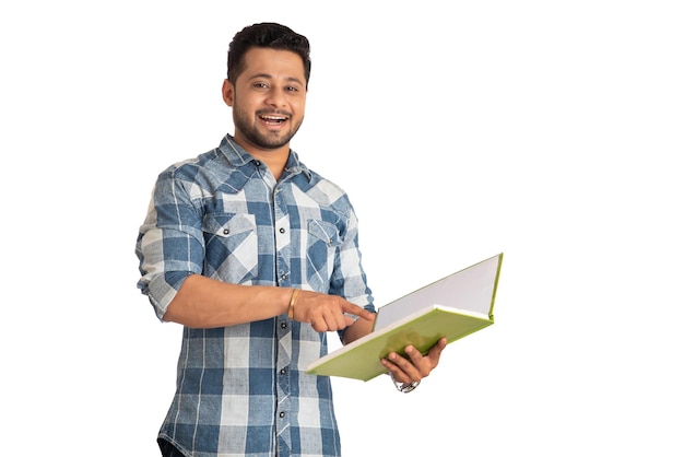 Joven hombre feliz sosteniendo y posando con el libro sobre fondo blanco.