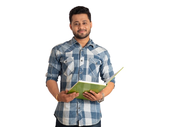 Joven hombre feliz sosteniendo y posando con el libro sobre fondo blanco.