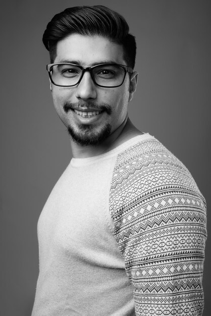 Joven hombre iraní barbudo con ropa casual contra la pared gris en blanco y negro