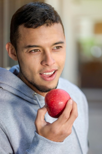 Joven hombre latino comiendo manzana fruta runner formato de retrato de invierno ejecutando entrenamiento deportivo fitness