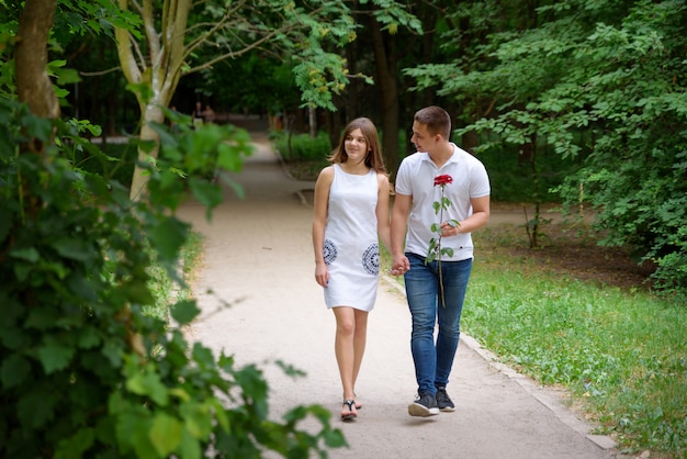 Joven hombre y mujer están caminando en el parque cogidos de la mano