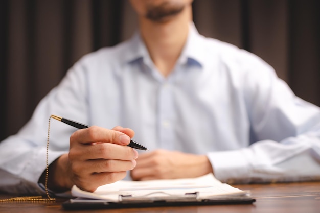 Un joven hombre de negocios asiático que trabaja en un trabajo de negocios de documentos en papel en un profesional de oficina moderno está feliz de iniciar una empresa con una nueva persona de trabajo en equipo mediante el uso de un plan de negocios para trabajar