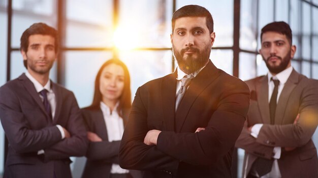 Joven hombre de negocios atractivo posando con su equipo de compañeros de trabajo