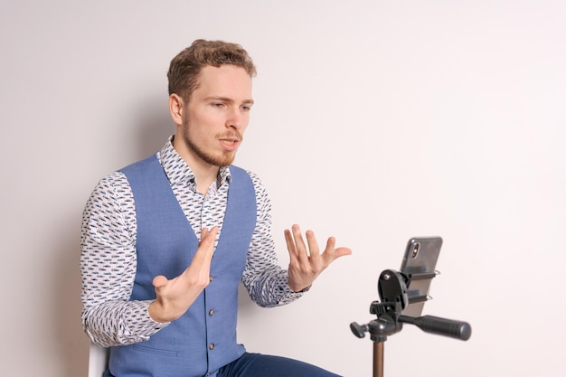 Un joven hombre de negocios con camisa gesticula mientras crea un video en las redes sociales