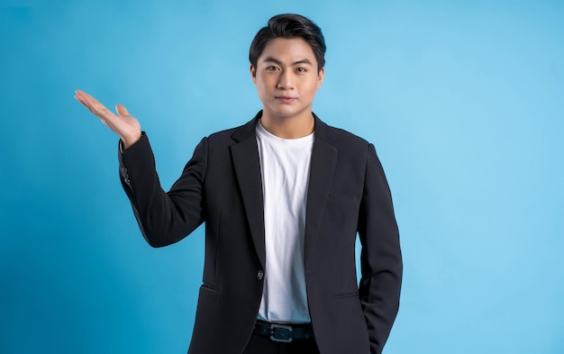 Joven hombre de negocios con un chaleco posando sobre un fondo azul.