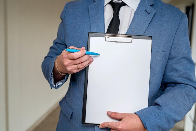 Joven hombre de negocios elegante con traje clásico y camisa blanca sosteniendo una tableta y un bolígrafo Concepto de hombre de negocios