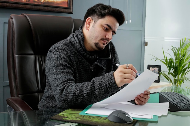 Un joven hombre de negocios está sentado en la oficina haciendo papeleo.