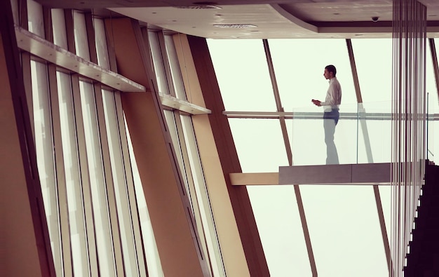 joven hombre de negocios exitoso en el ático que trabaja en tbalet, moderno y luminoso interior de apartamento de oficina dúplex con escalera y grandes ventanas