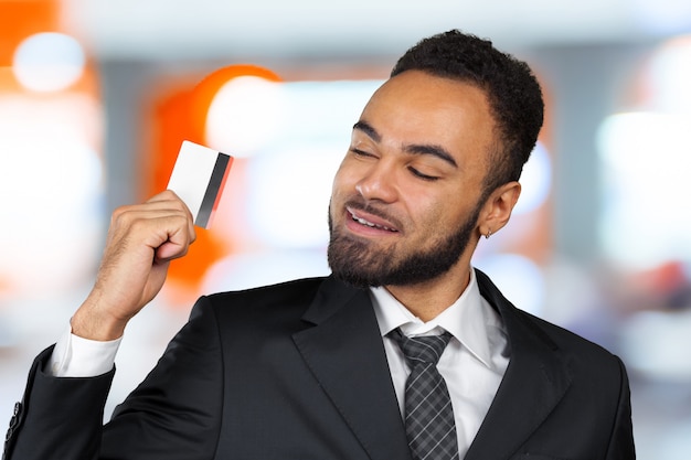 Joven hombre de negocios exitoso en un elegante traje clásico negro con una tarjeta de crédito de plástico