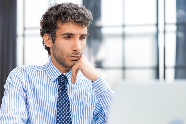 Joven hombre de negocios moderno que trabaja usando una computadora mientras está sentado en la oficina