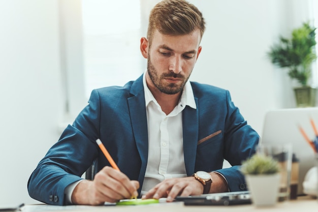 Joven hombre de negocios pensativo trabajando en los informes de un nuevo proyecto en la oficina.