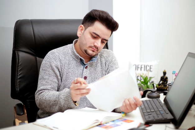 Un joven hombre de negocios tiene papeles en la mano y mira el papel.