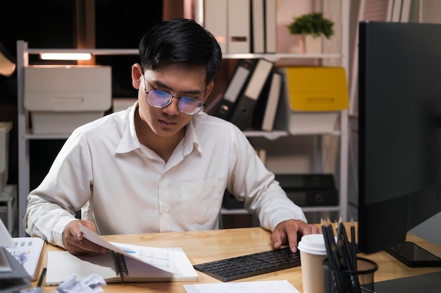 Joven hombre de negocios trabajando horas extras en un escritorio por la noche.
