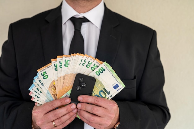 Joven hombre de negocios en un traje con abanico de billetes en euros Transacción financiera empresarial