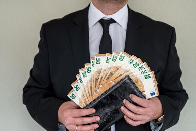 Joven hombre de negocios en un traje con ventilador de billetes en euros