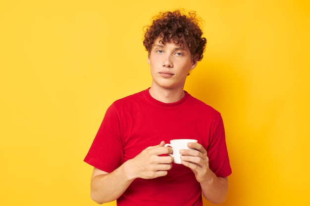 Joven hombre de pelo rizado taza blanca en manos de una bebida fondo aislado inalterado