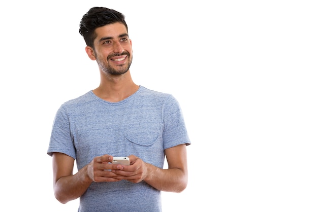 Joven hombre persa feliz sonriendo mientras sostiene el teléfono