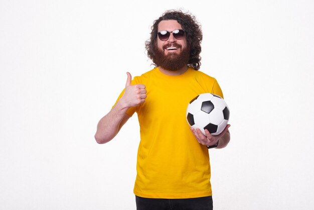 Un joven inconformista barbudo está sonriendo amablemente a la cámara