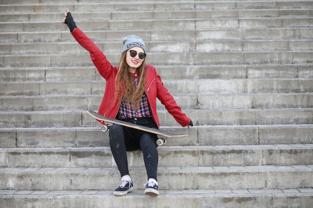 Una joven inconformista está montando una patineta. Amigas de las niñas a pasear por la ciudad con una patineta. Deportes de primavera en la calle con una patineta.