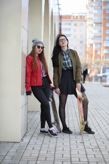 Una joven inconformista está montando una patineta. Amigas de las niñas a pasear por la ciudad con una patineta. Deportes de primavera en la calle con una patineta.