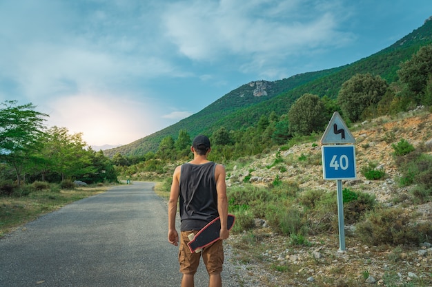 Joven inconformista sosteniendo un longboard fresco en la mano