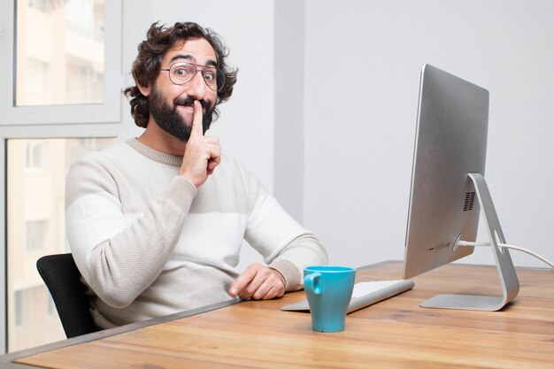 Joven independiente barbudo loco trabajando con su computadora