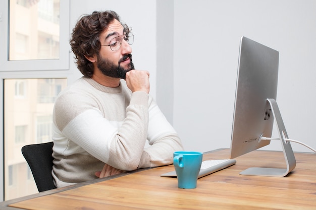 Joven independiente barbudo loco trabajando con su computadora