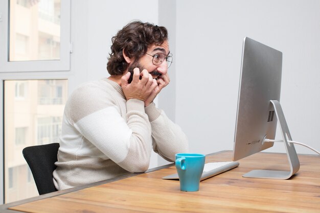 Joven independiente barbudo loco trabajando con su computadora