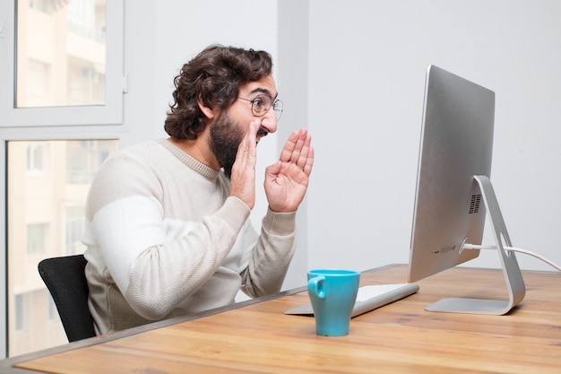 Joven independiente barbudo loco trabajando con su computadora