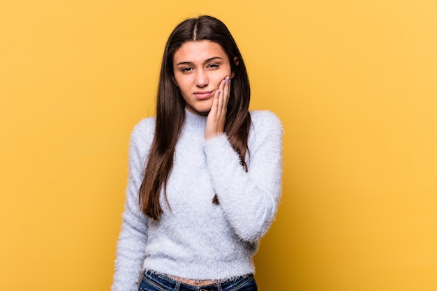 Joven india aislada sobre fondo amarillo con un fuerte dolor de dientes, dolor de muelas.