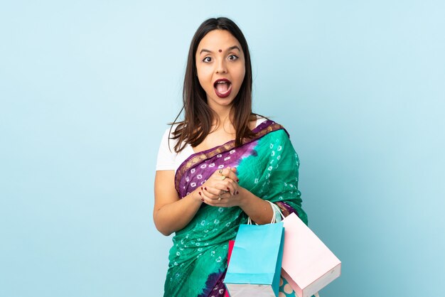 Joven india con bolsas de compras con expresión facial sorprendida