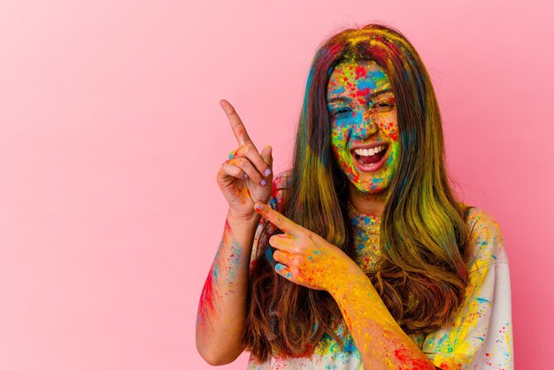 Joven india celebrando el festival sagrado aislado en blanco apuntando con los dedos índices a un espacio de copia, expresando entusiasmo y deseo.