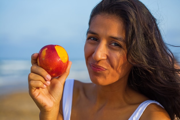 Joven India comiendo fruta en la playa