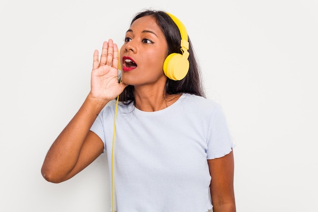 Una joven india escuchando música con auriculares aislada en un fondo blanco gritando