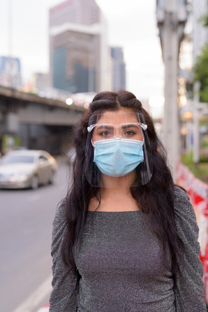 Joven india con máscara y protector facial en las calles de la ciudad