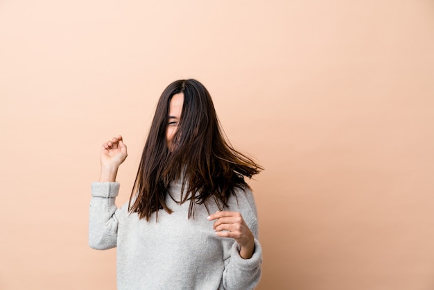 Foto joven india moviendo su cabello aislado sobre fondo beige