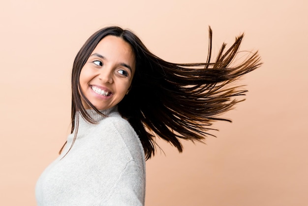 Foto joven india moviendo su cabello aislado sobre fondo beige